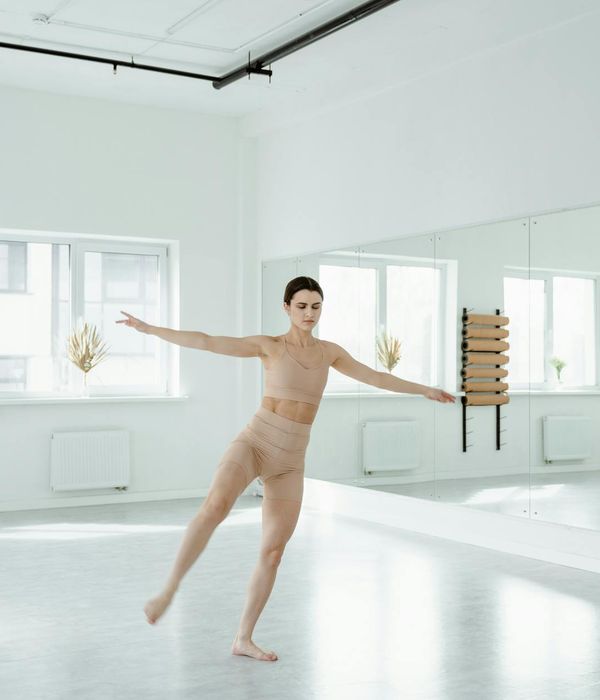 Woman performing a fluid, graceful exercise in a bright studio.